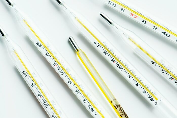 Several glass thermometers with yellow liquid arranged diagonally on a plain white background, symbolizing childhood mistakes.