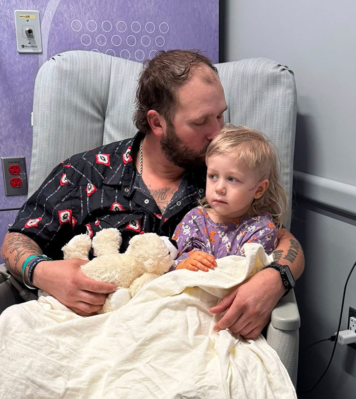 Man comforting toddler in chair at hospital after police fatally take down woman attacking toddler with knife at Walmart