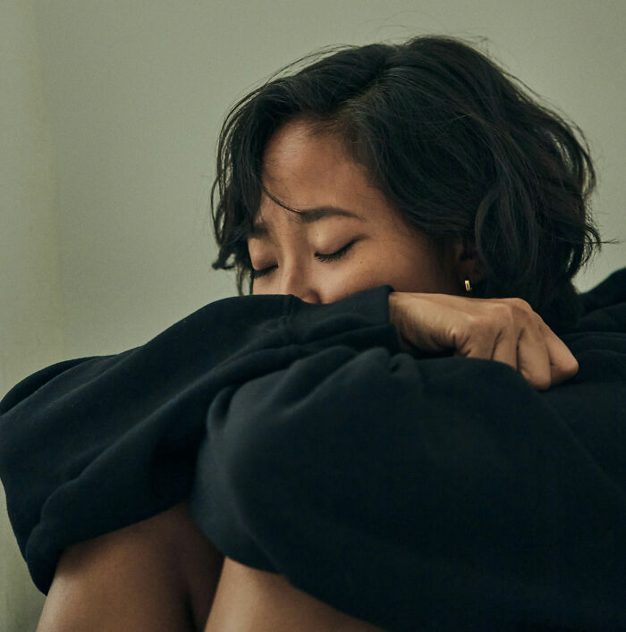 Woman with eyes closed hugging her knees, reflecting on horrendous things committed by best friends in life.