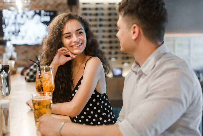 A young couple on a bar date, smiling and chatting over drinks, capturing moments before someone might leave mid-date.