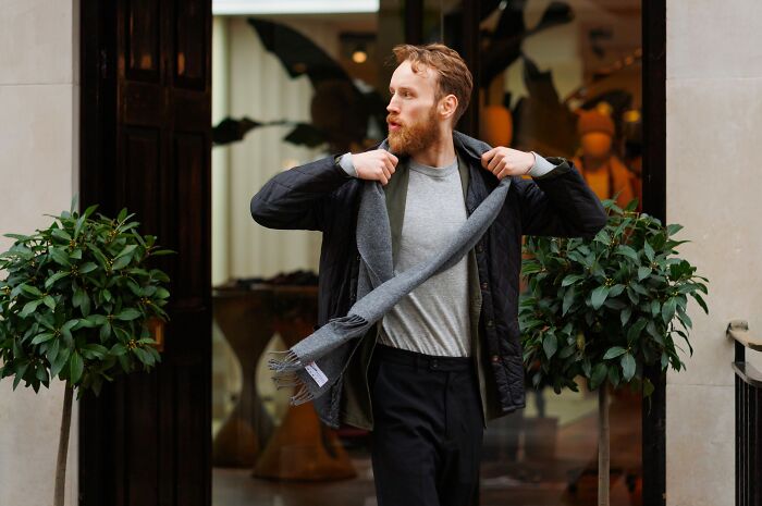 Man leaving mid-date, adjusting coat and scarf with a determined expression in an urban outdoor setting.