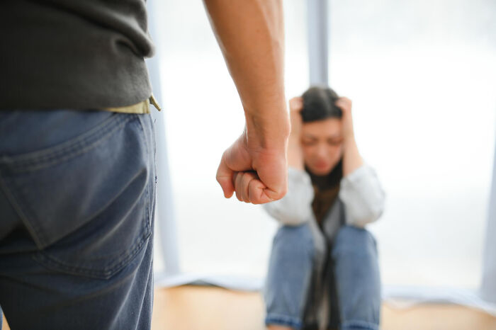 Man with clenched fist standing near distressed woman sitting on the floor, illustrating reasons people got up and left mid-date.