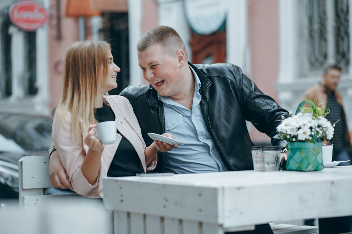 Couple enjoying a lighthearted moment at an outdoor cafe during a date, highlighting reasons people left mid-date.
