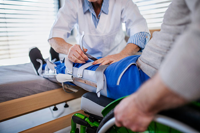 A medical professional adjusts a patient's leg brace, illustrating patient stories and medical care.