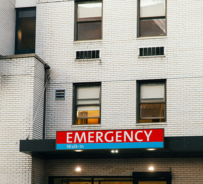 Exterior shot of a hospital with a red EMERGENCY Walk-In sign. Patient stories can be found here.