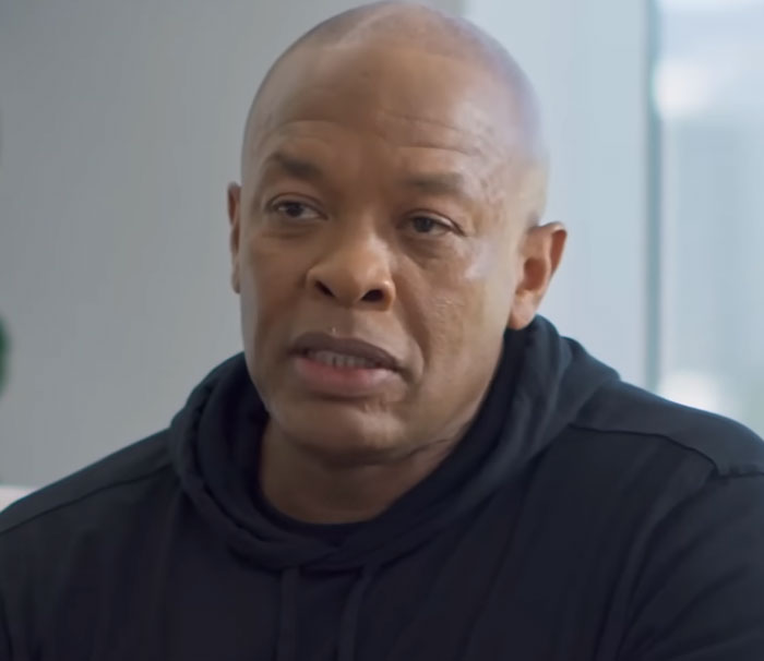 Man in a black hoodie speaking seriously in an indoor setting, related to disturbing celebrity facts.