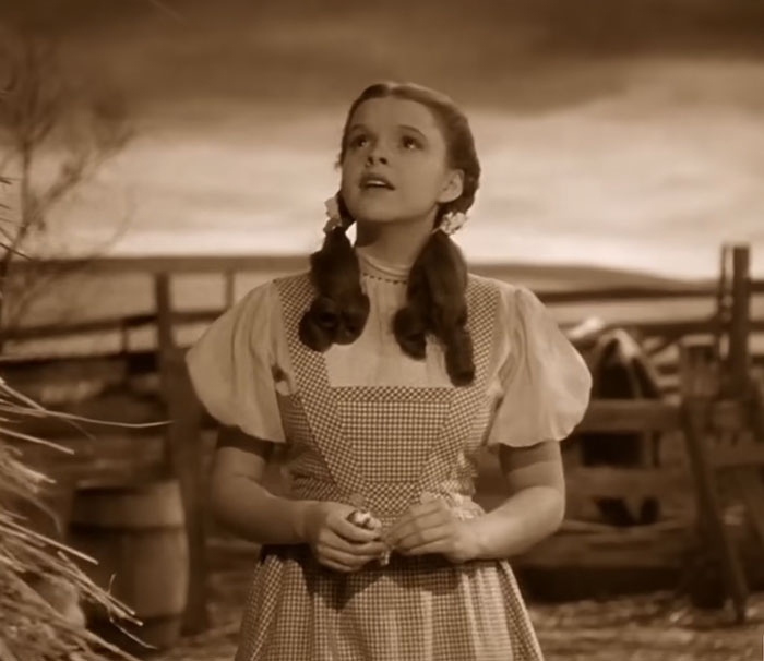 Sepia-toned image of a young woman in 1930s style dress amidst a rustic farm setting, evoking disturbing celebrity facts.