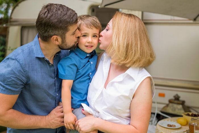 Young boy being kissed by both parents outside, illustrating heartbreaking things parents have told their kids.