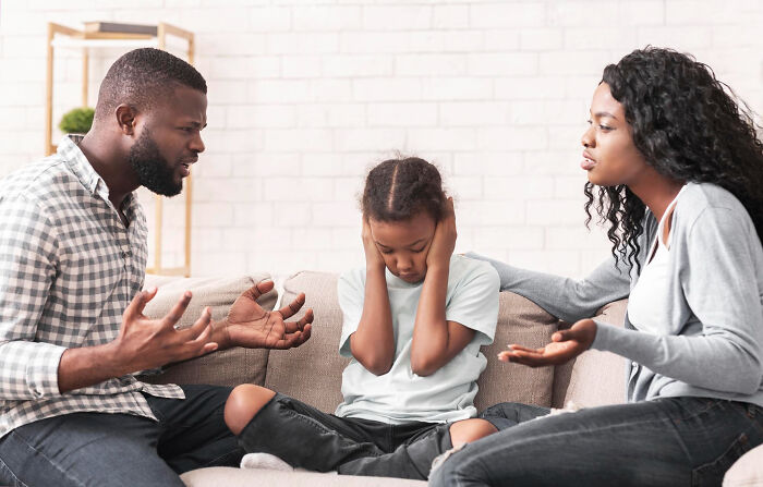 Parents angrily arguing while a child covers ears, depicting emotional impact of sickening and evil things parents say to kids.