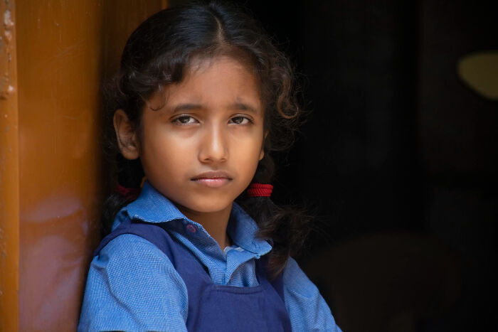 Sad young girl in a school uniform leaning against a wall, reflecting on sickening and evil things parents say to kids.