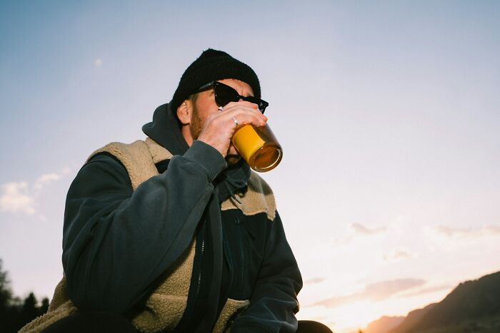 Person wearing sunglasses and a beanie drinking from a glass outdoors, depicting a sickening and evil moment parents told kids.