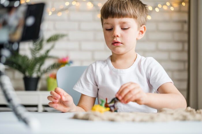 Young boy playing quietly at a table indoors, illustrating the impact of horrible things parents have told their kids.