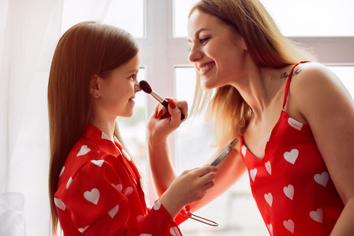 Mother and daughter smiling as the child applies makeup, highlighting moments before sickening and evil parenting words emerge.