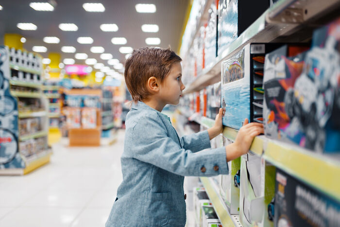 Young boy in a store aisle looking closely at toys, reflecting on horrible things parents have told their kids.