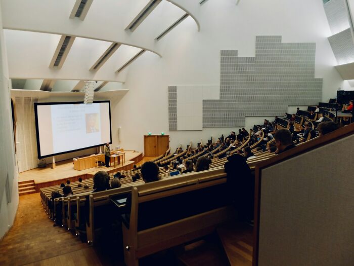 Students in a lecture hall with a speaker presenting on a large screen. Many rage quit for better learning environments.