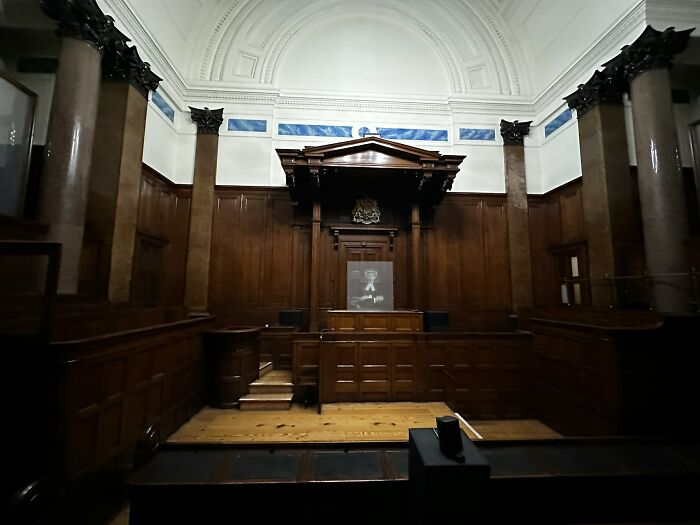 Empty historic courtroom with wooden paneling and columns, symbolizing unexpected and bizarre ways people passed away.