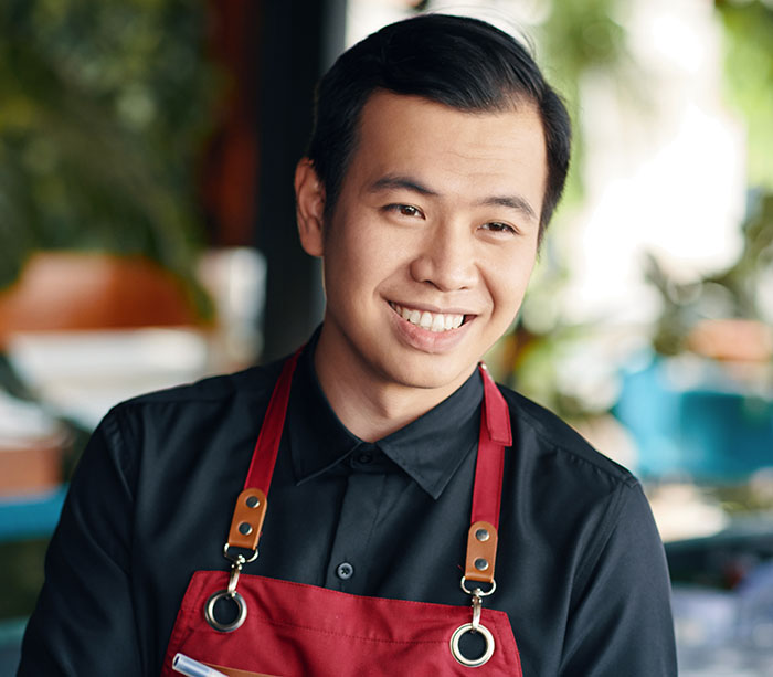 Smiling man in a red apron, representing people who know Chinese and Japanese amused by tattoo meanings.