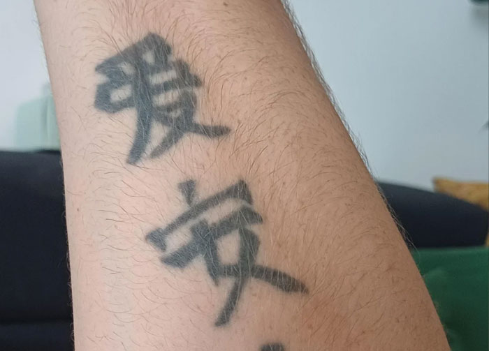 Tattoo on forearm with Chinese and Japanese characters, showcasing language tattoos that amused people familiar with them.