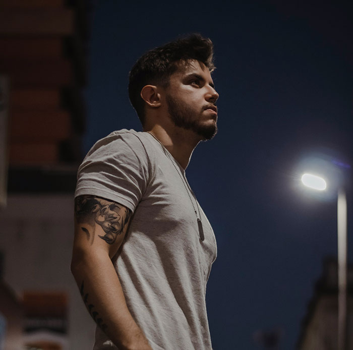 Young man with arm tattoo standing outdoors at night, a scene related to Chinese and Japanese tattoo meanings.