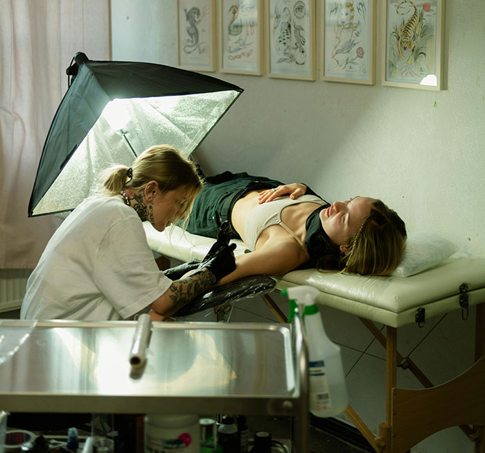 Tattoo artist creating a new design on a woman’s arm in a studio known for Chinese and Japanese tattoos.