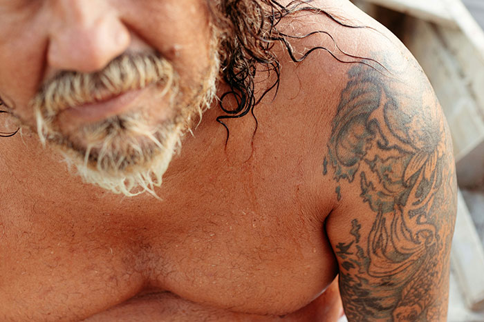 Close-up of a man with a detailed Asian-inspired tattoo on his shoulder, illustrating tattoos related to Chinese and Japanese.