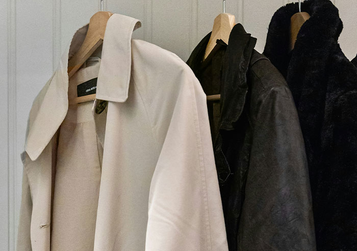 Coats hanging on wooden hangers in a closet, illustrating a scene related to coworkers in a casual workplace environment.