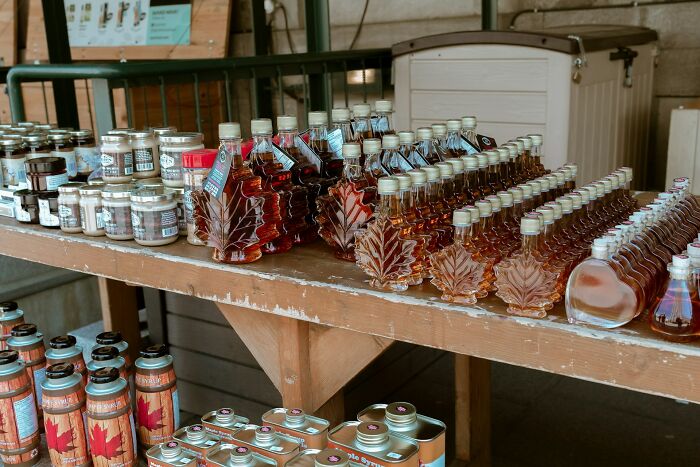 Bottles and jars of maple syrup on display on wooden tables, items TSA has had to confiscate.