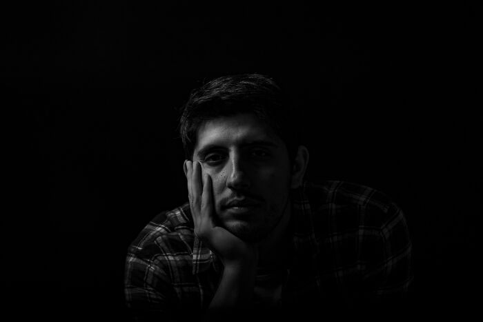 Young man in a plaid shirt looking contemplative in low light, reflecting on unexpected DNA test results.