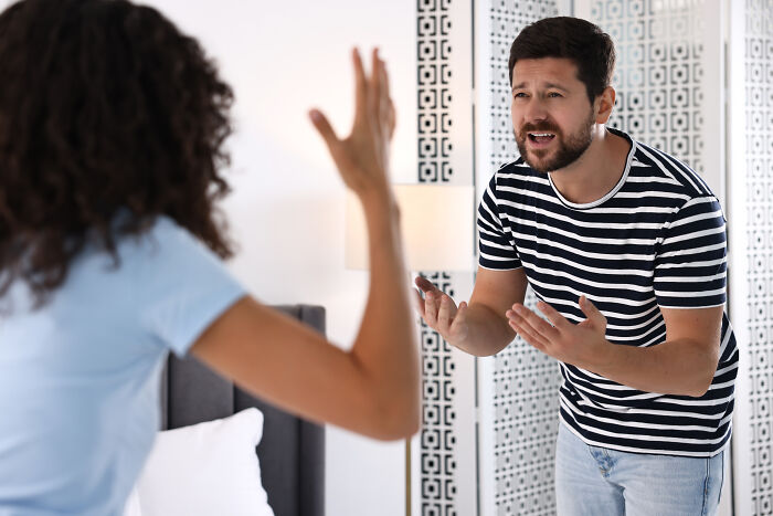 A man and woman arguing, with the woman's back to the camera. The man looks distressed, possibly after finding out he was being cheated on.