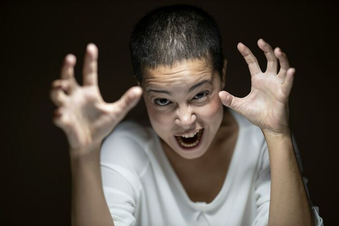 Person making a playful scary face with hands raised, illustrating bizarre family moments people now realize.