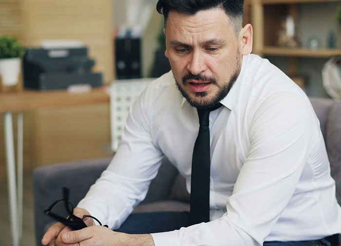 A man in a white shirt and black tie looking distraught, perhaps an employee getting revenge on a horrible boss.