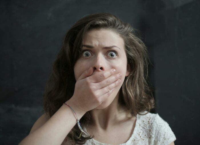 Woman with wide eyes covering her mouth, showing surprise after discovering unexpected results from DNA tests.