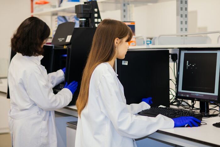 Two scientists in lab coats and gloves working with medical equipment, highlighting hidden truths about hospitals.