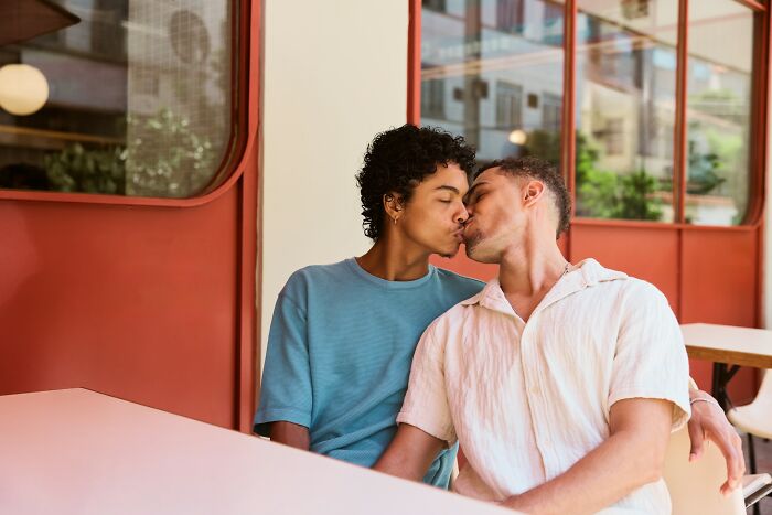 Two men share a tender kiss at a cafe, illustrating love and resilience in stories of how life dealt with horrible bullies.