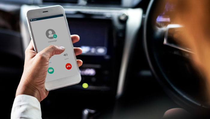 Person holding smartphone in car, receiving a call related to single mom expecting friend to drop work and care for autistic kid