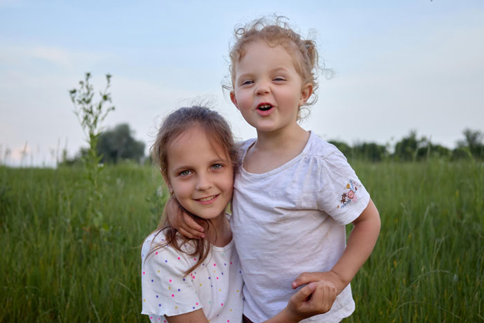 Two children in a grassy field, representing a single mom relying on a friend to look after her autistic kid.