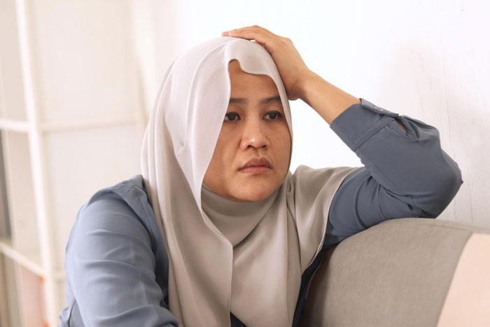 A thoughtful Muslim woman in a hijab, looking concerned. Christian bride excludes Muslim best friend, wedding, gift registry.