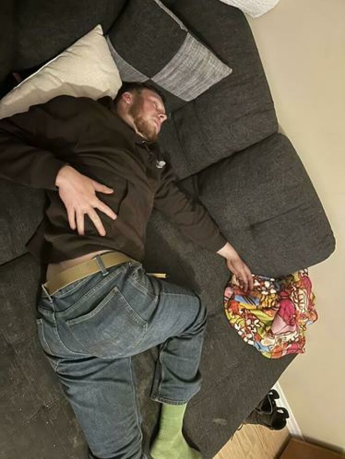 Man caught sleeping on a couch in a relaxed position with colorful blanket nearby, showcasing hilarious and unhinged sleeping ways.