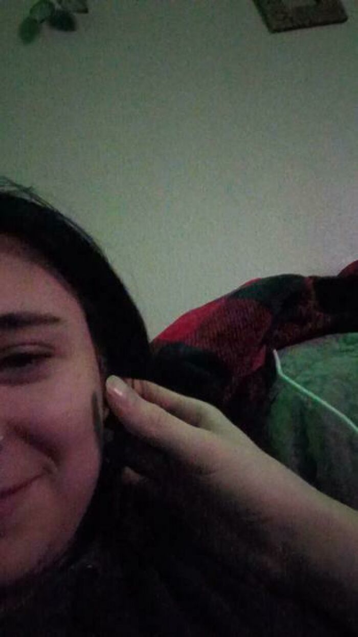 Person caught sleeping in a relaxed position, smiling softly while resting with a hand gently touching their face.