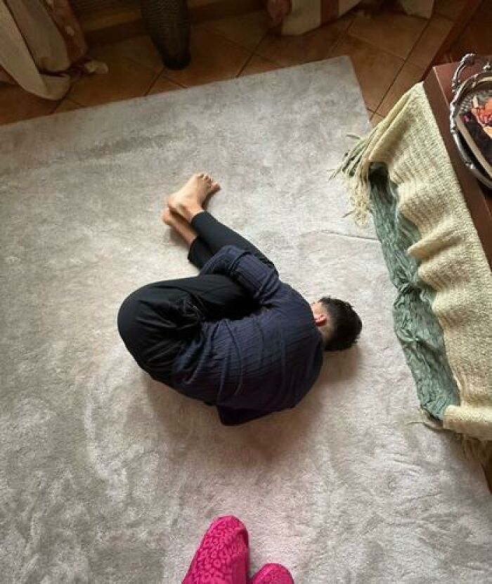 Person sleeping on floor curled up in a fetal position showing one of the hilarious and unhinged ways people caught sleeping.