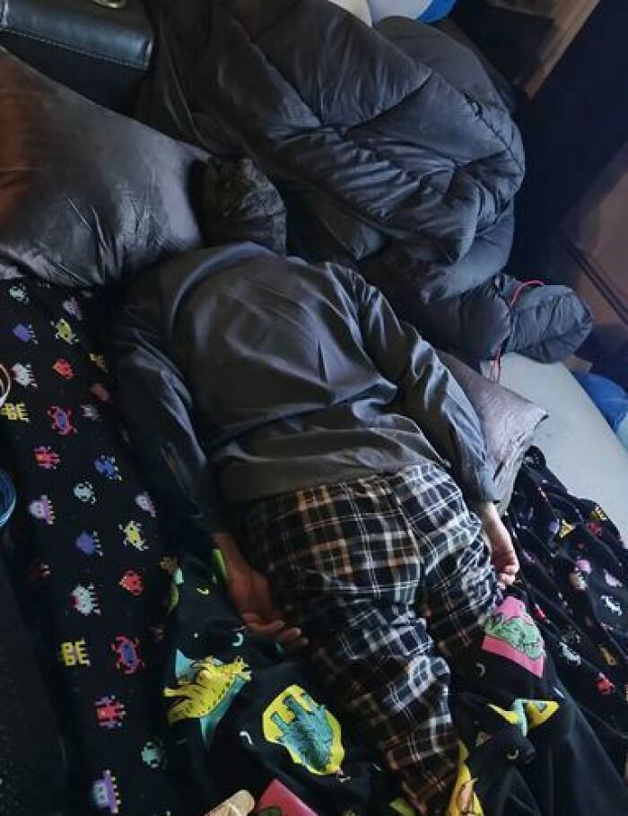 Person caught sleeping in hilarious and unhinged way, lying face down in pajamas on a colorful blanket.