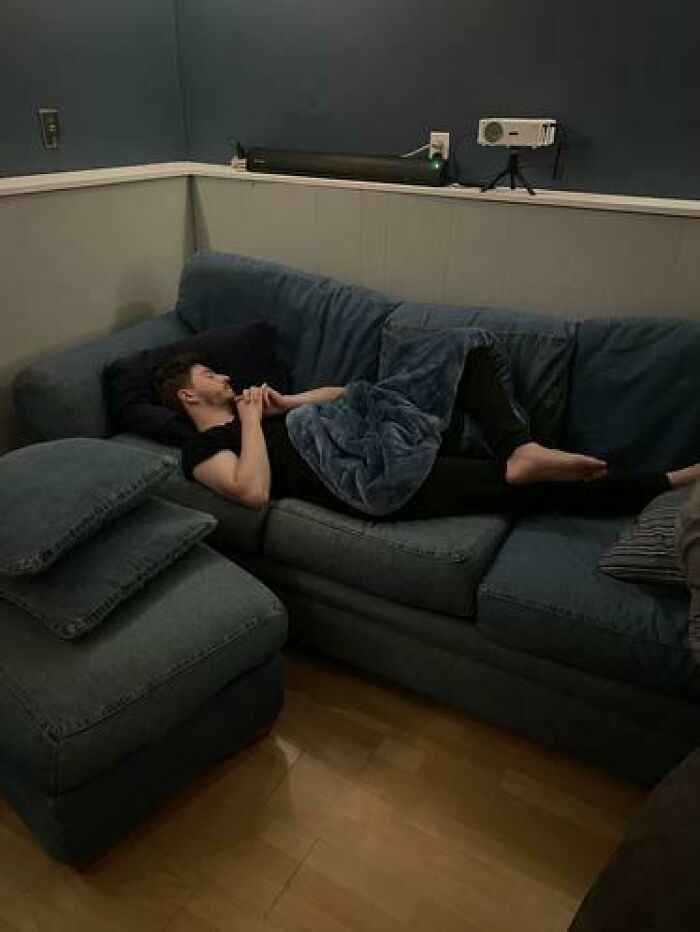 Person sleeping on a blue couch in a relaxed pose, captured among hilarious and unhinged sleeping moments.