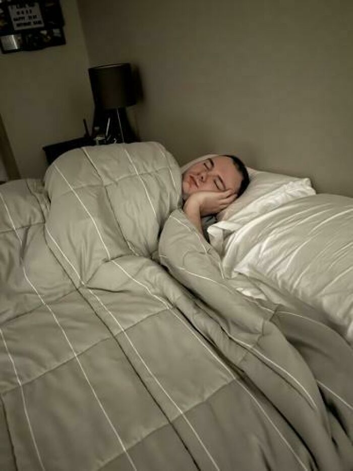 Person caught sleeping wrapped in a blanket with head resting on hand in a bedroom setting, relaxing comfortably in bed