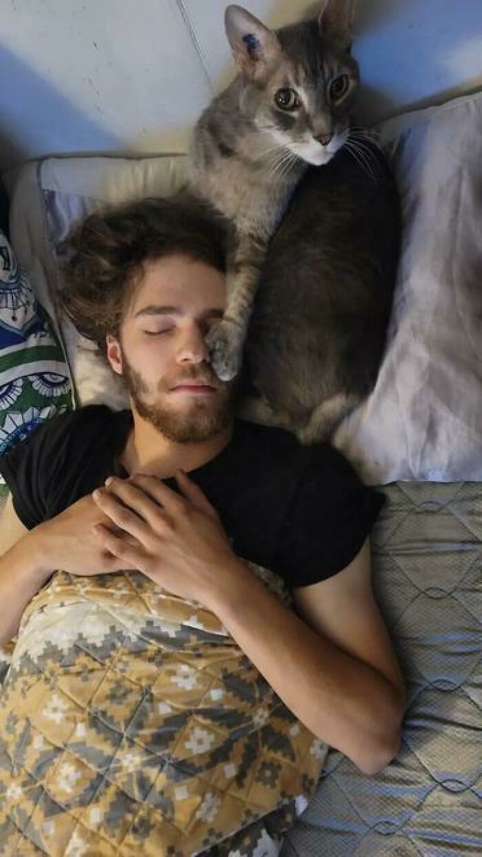 Man sleeping with cat lying on his face in one of the funniest people caught sleeping in hilarious ways.