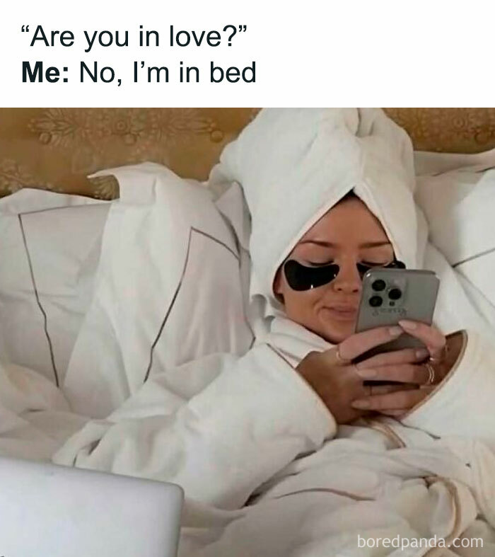 Woman in a bathrobe and towel scrolling on phone in bed, representing daily meme scrolling for a chuckle and light humor.