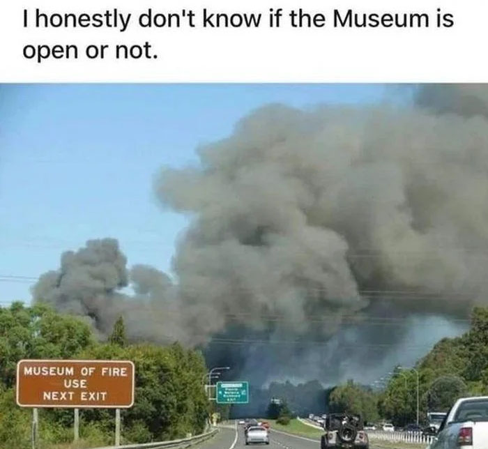 Highway scene with heavy smoke and a Museum of Fire sign, humorously questioning if the museum is open, safe-for-work meme.