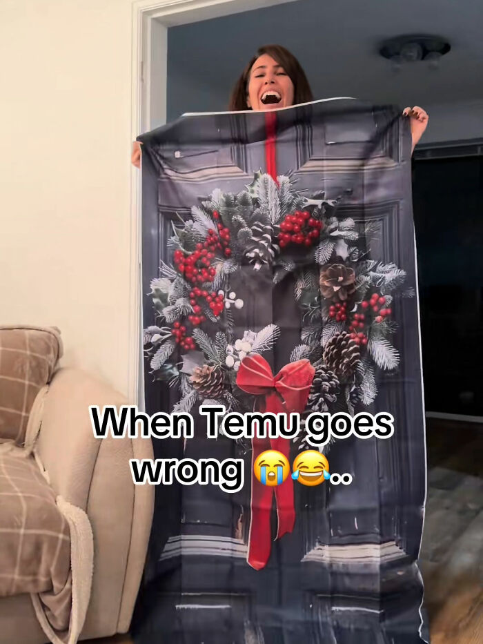 Woman holding a large Temu order with a holiday wreath print, reacting to a funny Temu purchase fail at home.