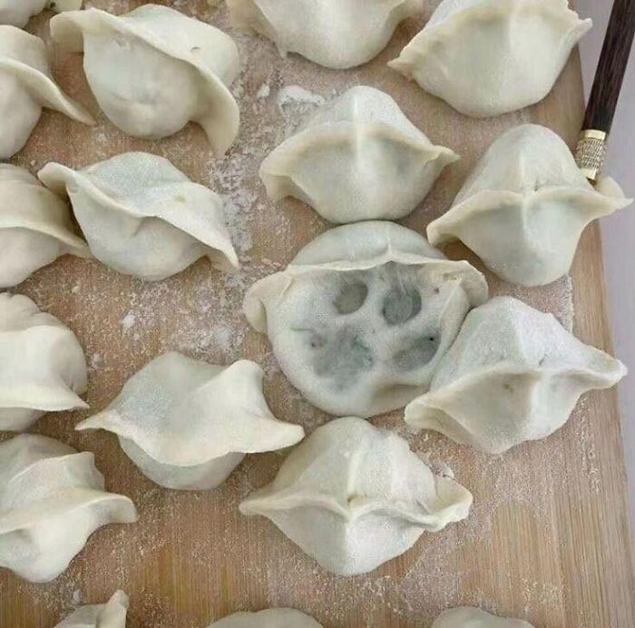 Dumplings laid out on a wooden board with one dumpling resembling a cat's paw print, highlighting funny cat jobs.