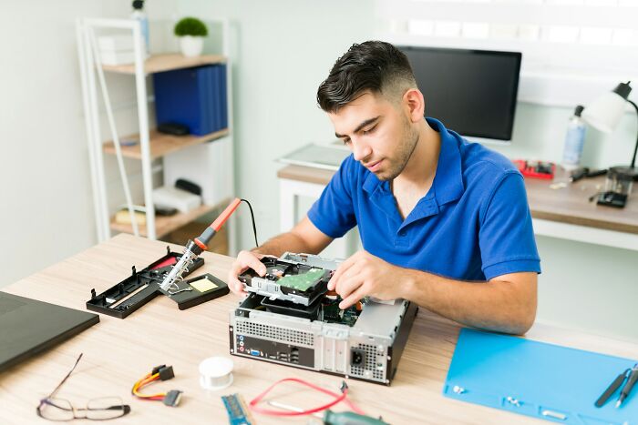 Young man repairing computer hardware, illustrating random life decisions leading people to the right place through honest stories.