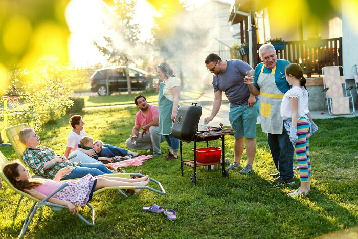 Family and friends enjoying a backyard barbecue on a sunny day, illustrating moments of weaponized incompetence.